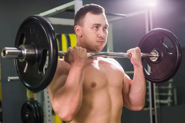 Muskulöser junger Mann stemmt Gewichte im Fitnessstudio — Stockfoto