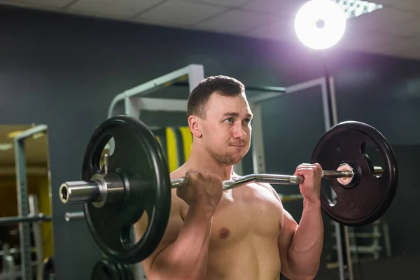 Muskulöser junger Mann stemmt Gewichte im Fitnessstudio — Stockfoto