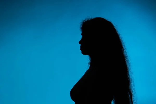 Silueta de mujer joven desnuda sobre fondo azul —  Fotos de Stock