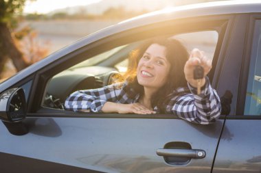 Yeni araba, satın alma ve sürücü kavram - genç kadın gösteren anahtar arabada