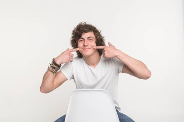 Kendinden emin gösterilen ve işaret parmak ağız ile gülümseyen yakışıklı delikanlı. İyi bir ruh hali ve insanlar kavramı.