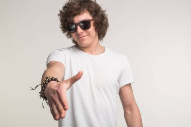 Dostluk, işbirliği ve tebrik kavramı - kıvırcık erkekte gülümseyen bir el için el sıkışma veren beyaz tişört