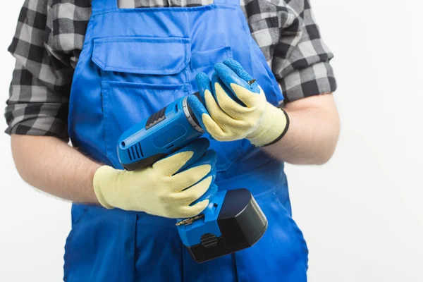 Close-up of builder men with screwdriver wearing gloves and blue overalls.