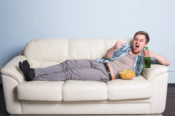 Pria dengan bir dan keripik menonton TV di rumah — Stok Foto