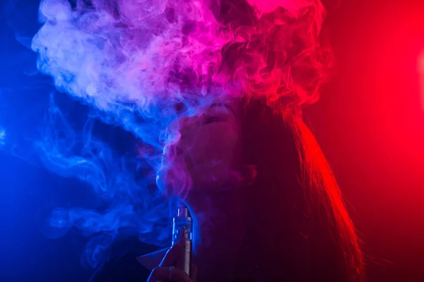 Retrato de mulher jovem em néon fumaça vermelha e azul com vape ou e-cigarros — Fotografia de Stock