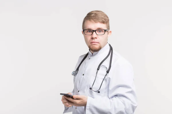 Retrato de médico masculino em estúdio com telefone nas mãos — Fotografia de Stock
