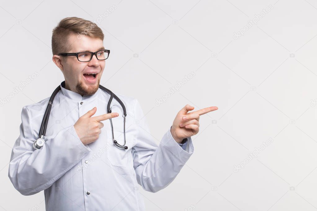 Happy young doctor in studio pointing left