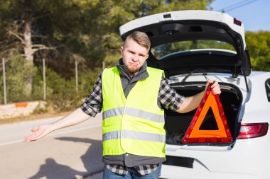 O kırmızı bir üçgen acil işaret edecek bir sorun bir araba ile adam