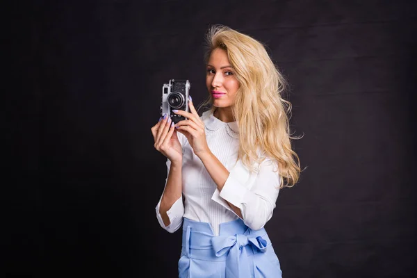 Концепция моды и красоты - красивая блондинка в белой рубашке с ретро фотокамерой на тёмном фоне — стоковое фото