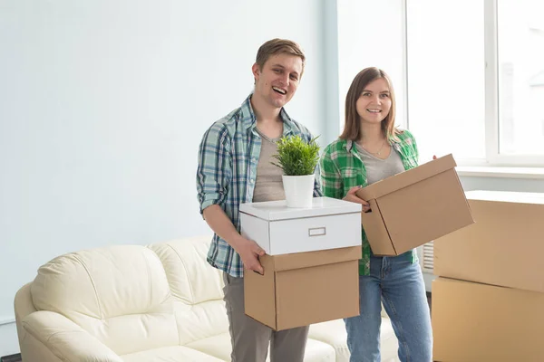 Feliz jovem casal segurando caixas móveis com sofá no fundo . — Fotografia de Stock