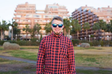 Güleryüzlü genç adam arka plan park ve Binalar günbatımı bakarak