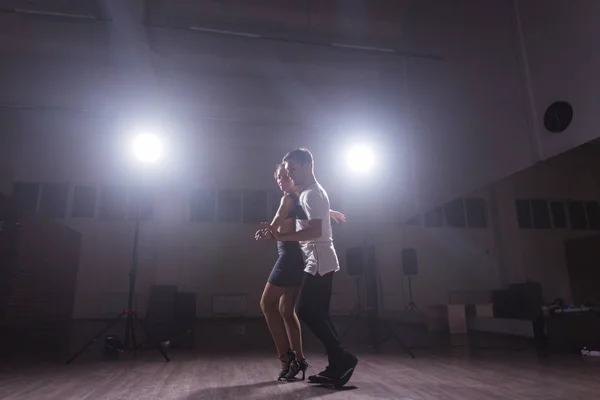 Casal jovem dançando danse social kizomba ou bachata ou semba ou taraxia em fundo de aula de dança — Fotografia de Stock