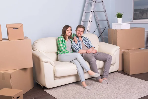 Додому, люди і рухома концепція- Приваблива молода пара сидить на дивані — стокове фото
