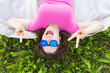 Yaz, tatil ve eğlence kavramı - en iyi genç komik kadın parkta çim üzerinde yalan güneş gözlüğü takıyor portresi