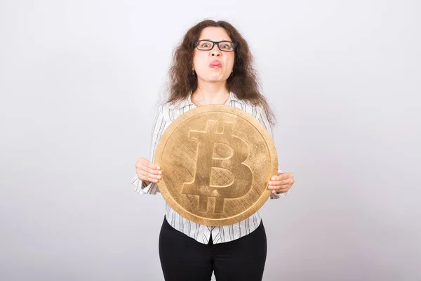 Joven enojada sosteniendo bitcoin grande de oro y mostrando la lengua - cripto moneda, dinero web y el concepto blockchain — Foto de Stock