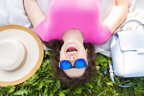 Yaz, tatil ve eğlence kavramı - en iyi genç komik kadın parkta çim üzerinde yalan güneş gözlüğü takıyor portresi