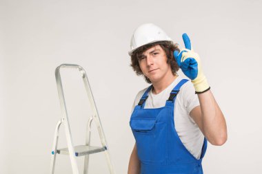 Yukarı dönük ve bir merdiven ile infront ayakta beyaz kask içinde yakışıklı Oluşturucusu portresi.