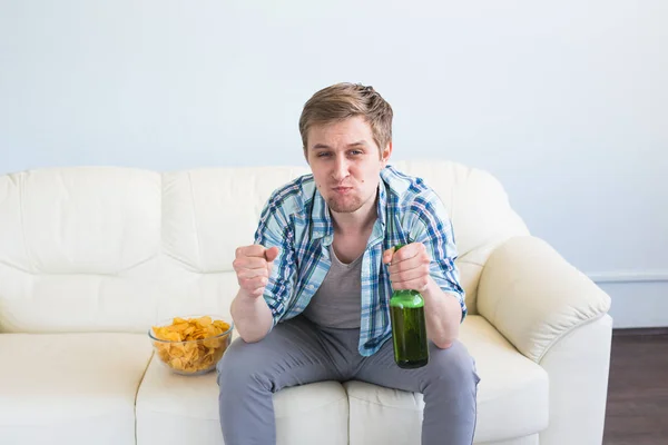 Чоловік з пивом і чіпсами дивиться телевізор вдома — стокове фото