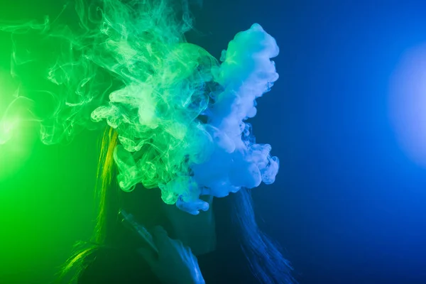 Mujer joven que fuma vapor o cigarrillo electrónico en luz de neón — Foto de Stock