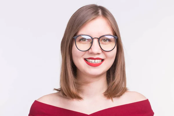 Móda a lidé koncept - zblízka portrétní mladá usmívající se žena v brýlích s červenými rty na bílém pozadí — Stock fotografie
