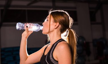 Fitness genç kadın içme suyu şişe. Kas genç erkek spor salonunda egzersiz bir mola.