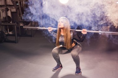 Güzel kadın bir spor salonunda barbell ile çalışma dışarı