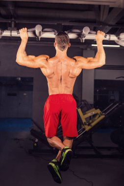 Yatay çubuk spor salonunda egzersiz yetişmek yapan güçlü genç erkek