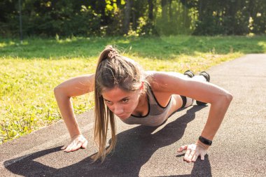 Fitness kadın açık çapraz eğitim egzersiz sırasında şınav. Güzel genç ve formda fitness spor modeli eğitim dışında park