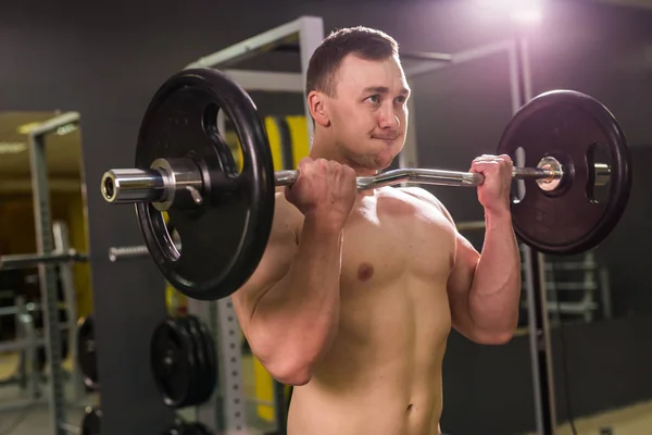 Kraftvoller Bodybuilder, der die Übungen mit der Langhantel macht. Stärke und Motivation. — Stockfoto