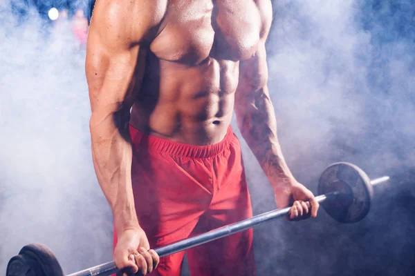 Gros plan de bodybuilder faire les exercices avec haltère. Homme fort avec torse nu sur fond sombre. Force et motivation . — Photo