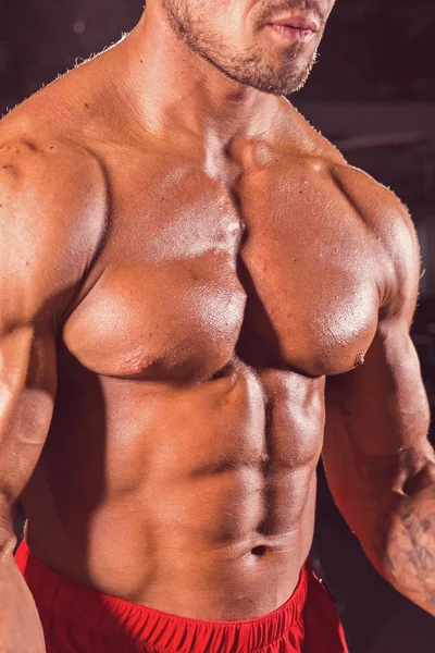 Primer plano de musculoso joven levantando pesas en el gimnasio — Foto de Stock