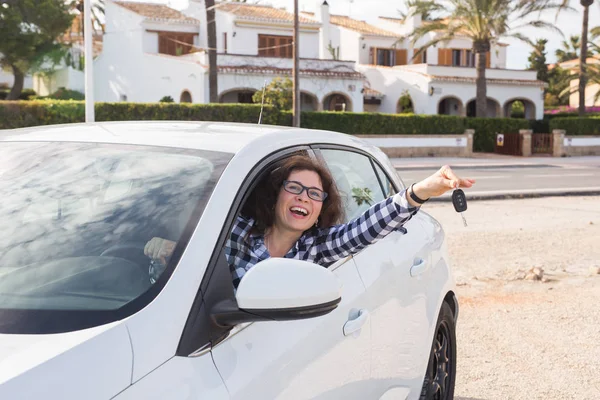 New car, purchase and driver concept - Happy woman showing key in a car