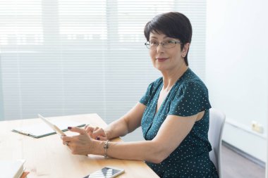 Teknoloji, iş ve insan kavramı - orta yaşlı kadın ofiste tablet kullanma