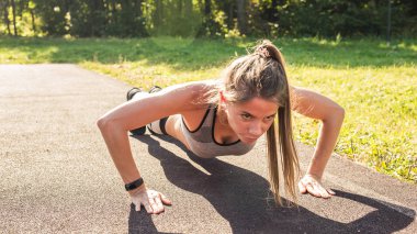 Genç kadın açık havada şınav yaparak egzersiz yerleştirmek.