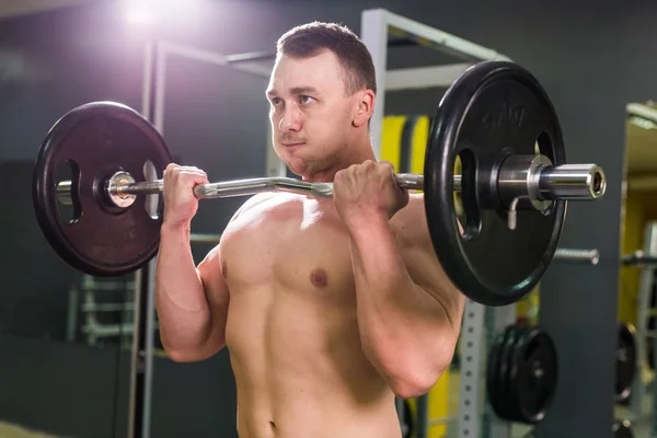 Kraftvoller Bodybuilder, der die Übungen mit der Langhantel macht. Stärke und Motivation. — Stockfoto