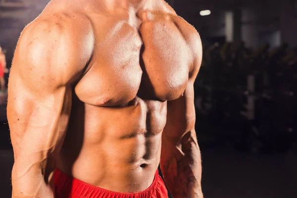 Primer plano de musculoso joven levantando pesas en el gimnasio — Foto de Stock