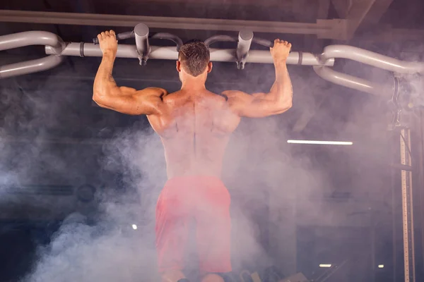 Pohledný svalnatý muž s dokonalé tělo dělá Pull Ups v tělocvičně — Stock fotografie