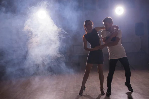 Dançarinos habilidosos se apresentando na sala escura sob a luz do concerto e fumaça. Casal sensual realizando uma dança contemporânea artística e emocional — Fotografia de Stock