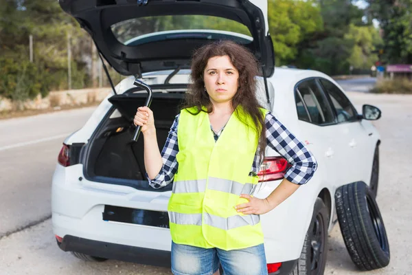 Mladá žena drží klíče v pozadí rozbité auto — Stock fotografie