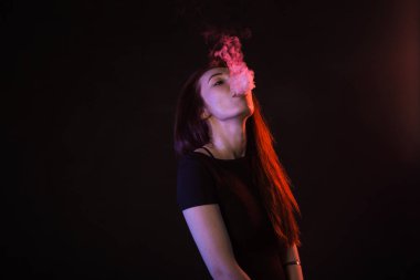 Neon ışık ve duman e-sigara veya vape siyah arka plan üzerine genç kadın