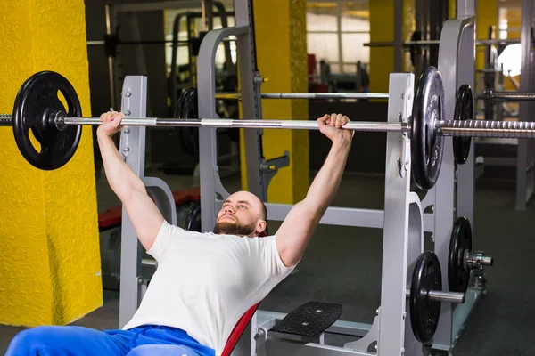 Sport, fitness, training and people concept - Man during bench press exercise in gym