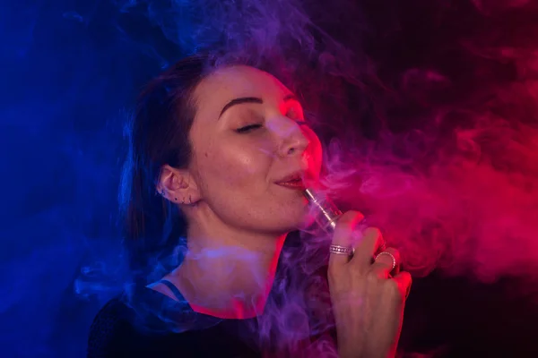 Gozando mulher com vape ou e-cigarro em fumaça e luz de néon — Fotografia de Stock