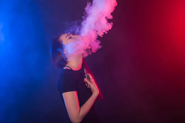 用 vape 或电子香烟在彩色霓虹灯烟雾中的女孩肖像. — 图库照片