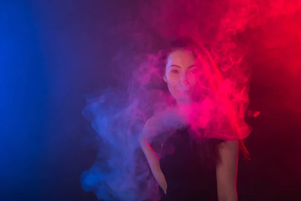 Młoda kobieta palenia vape lub e papieros w neon light — Zdjęcie stockowe