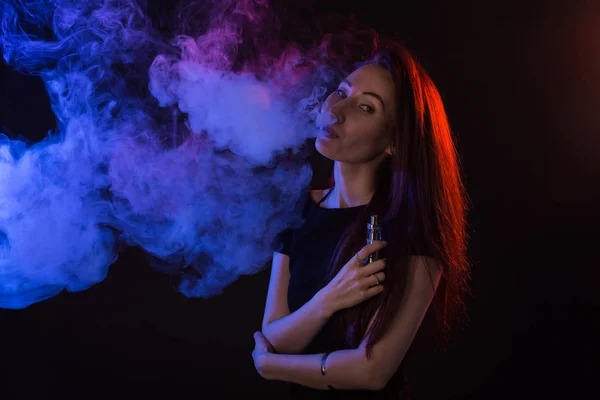 Młoda kobieta palenia vape lub e papieros w neon light — Zdjęcie stockowe