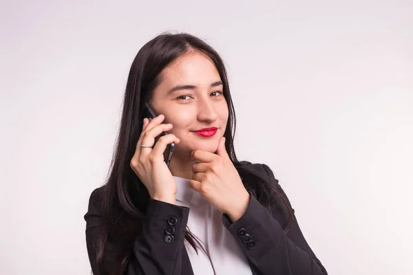 Schöne asiatische Mädchen in formeller Kleidung mit Telefon auf weißem Hintergrund — Stockfoto