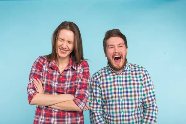 Divertida pareja joven riendo y tonteando juntos sobre fondo azul . — Foto de Stock