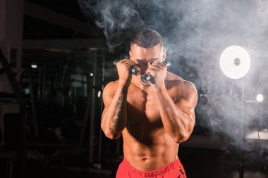 Boks egzersizleri yapıyorsun, tam isabet dumbbells ile güçlü bir adam. Sportif kaslı erkek fotoğrafı. Güç ve motivasyon