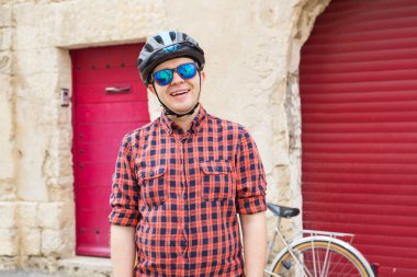 Artalan kırmızı açık bisiklet ile kask, güneş gözlüğü ve kırmızı gömlek, Genç adam