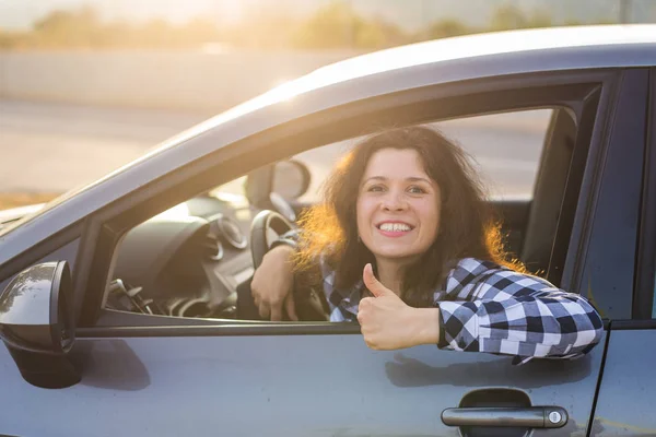 Šťastná žena ukazuje palcem a řídí nové auto. Pozitivní tvář výraz — Stock fotografie